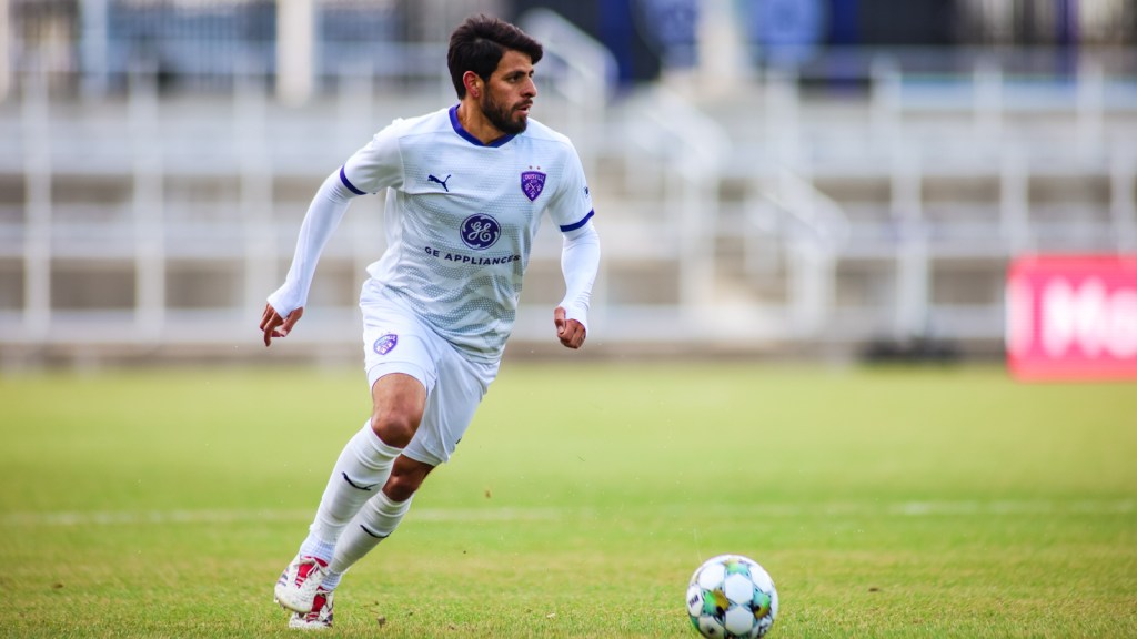 A soccer player plays with the ball at his feet.