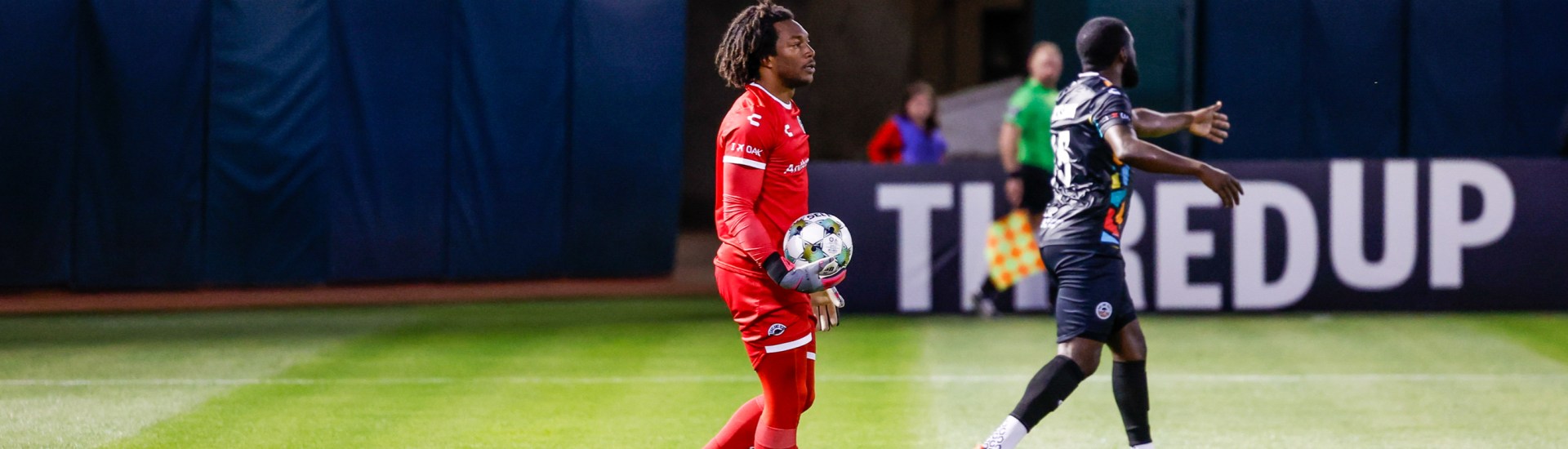Kendall McIntosh holding a soccer ball on the field.