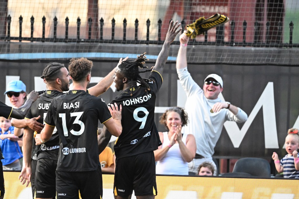 Hounds players (from left) Sean Suber, Luke Biasi and Emmanuel Johnson celebrate in front of fans after Suber's goal in the team's 5-0 win over Oakland Roots SC on July 13, 2024 at Highmark Stadium. (Photo: Matt Hawley/For Riverhounds SC)