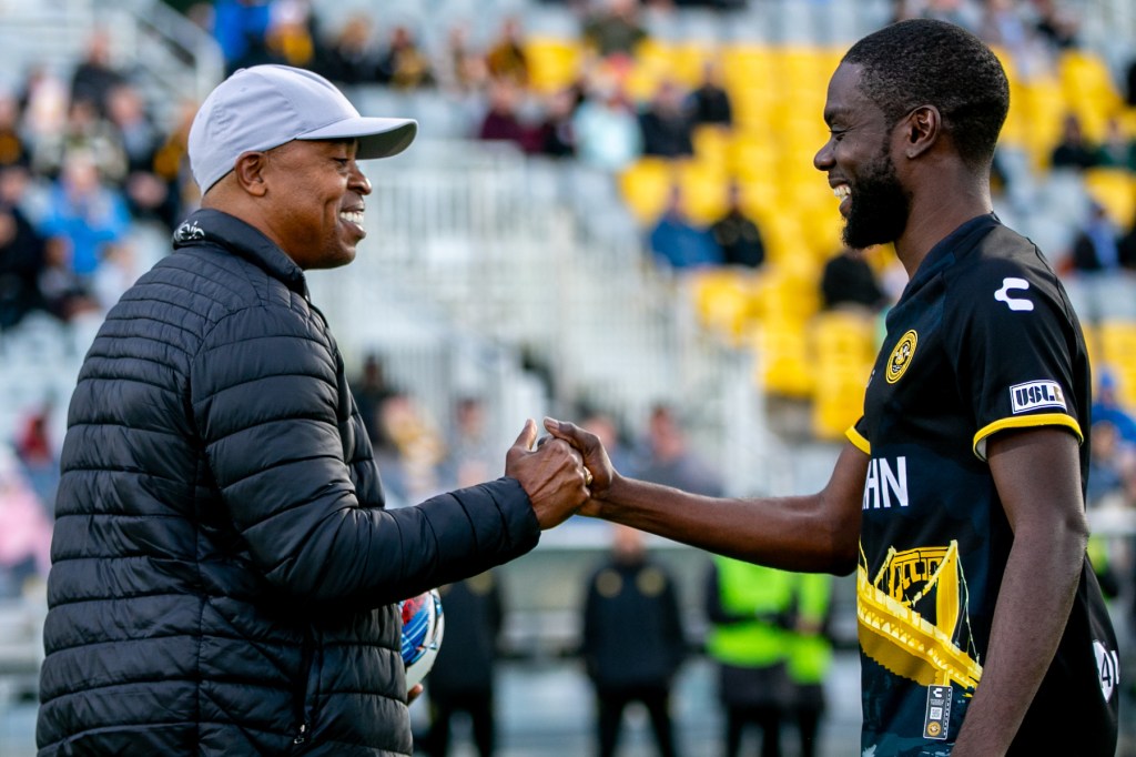 Kenardo Forbes greets David Flavius, who presented the match ball as Forbes eclipsed Flavius' record for most appearances in a Riverhounds uniform. (Photo: Chris Cowger/Riverhounds SC)
