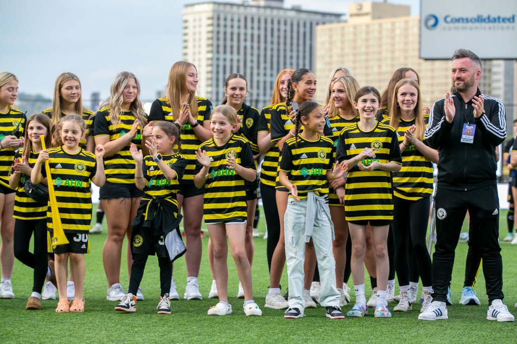 Riveters head coach Scott Gibson and girls players from the Riverhounds Development Academy cheer on the field after the announcement of Pittsburgh's W League team — later to be named the Riveters — before a Riverhounds match on April 27, 2024, at Highmark Stadium. (Photo: Chris Cowger/Riverhounds SC)