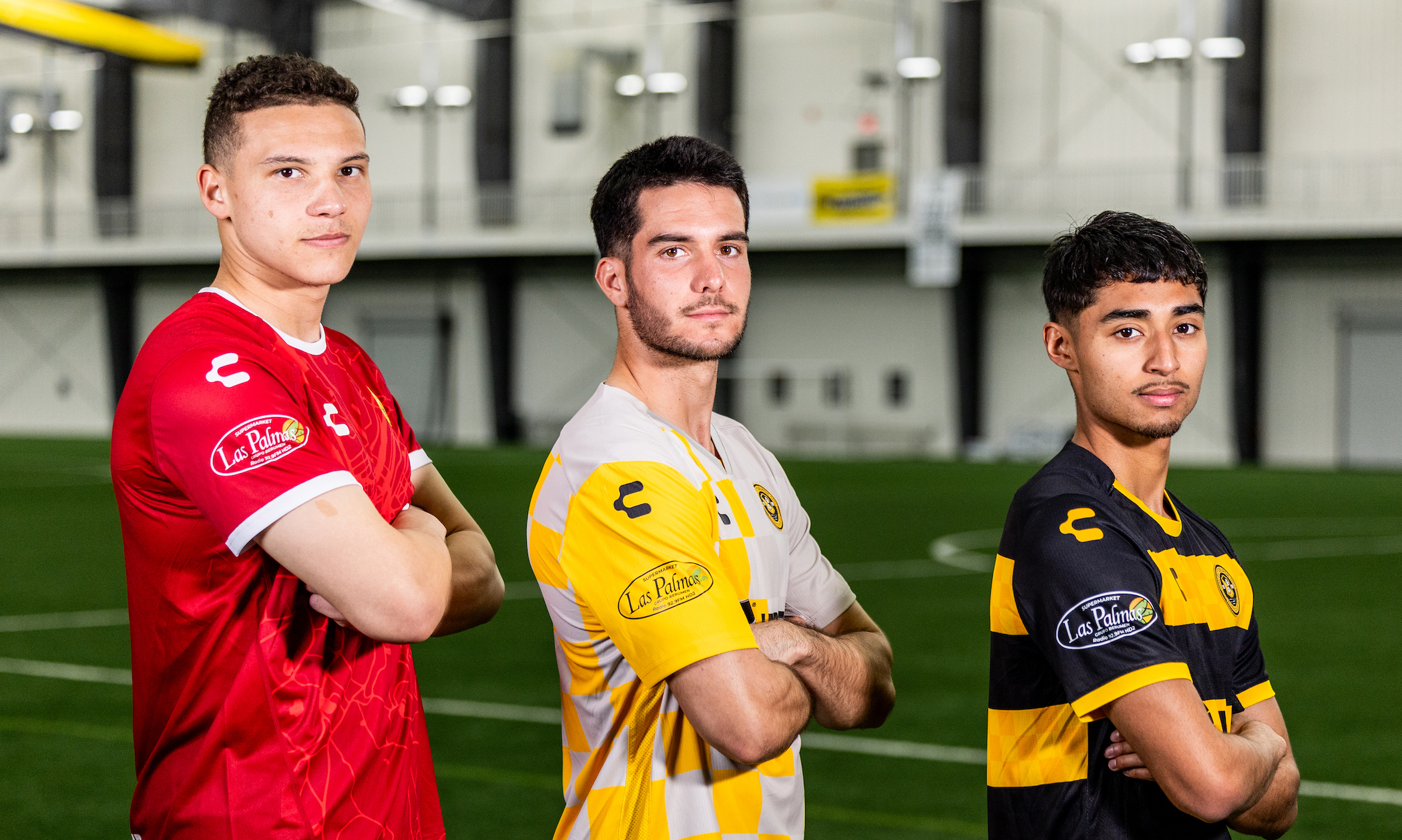 Riverhounds players Jacob Randolph, Beto Ydrach and Jorge Garcia pose in the club's kits with the logo of new sleeve sponsor Las Palmas Pittsburgh on display. (Photo: Ryan Shaffer/Riverhounds SC)